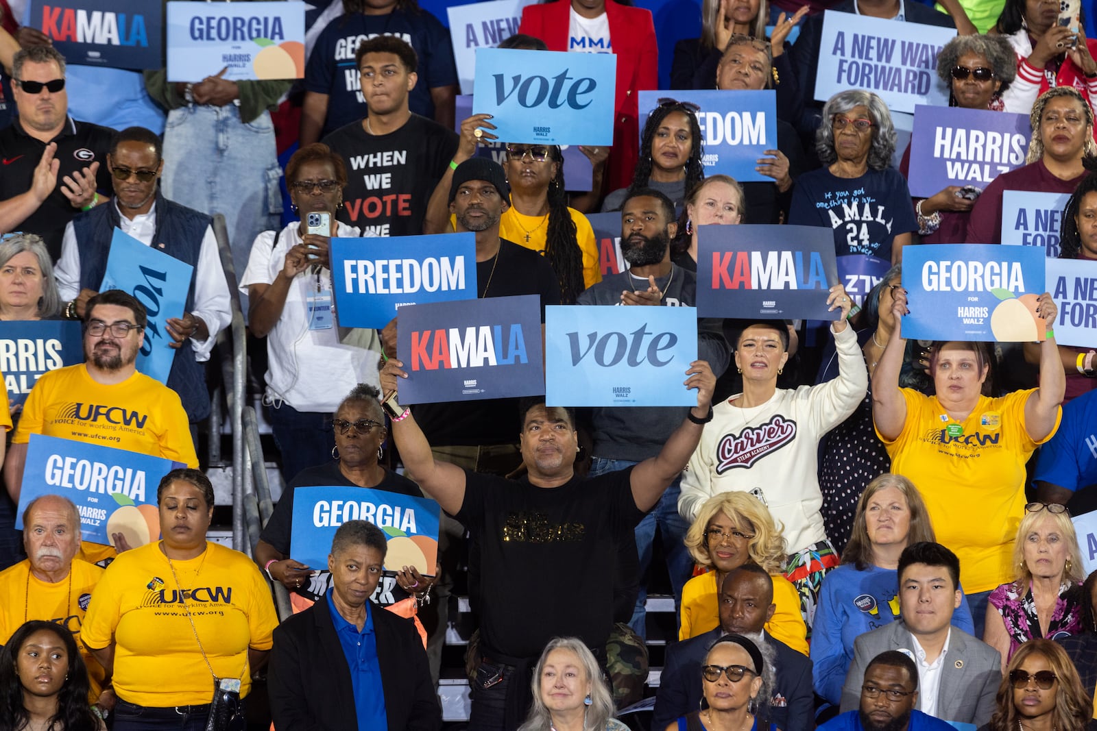 Supporters hold up signs during a campaign rally with Vice President Kamala Harris in Clarkston on Thursday.