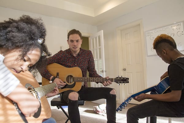 James Shealy (center), a music instructor, strums along as he walks through chords with Aryanna Maymi-Booker (left), 9, and Auvalli Booker (right), 9. REANN HUBER / REANN.HUBER@AJC.COM