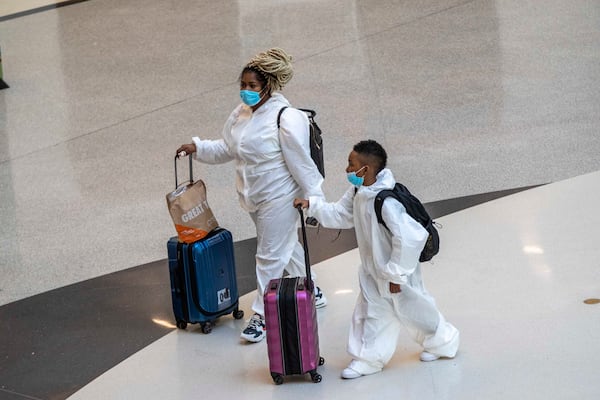 11/23/2020 �  Atlanta, Georgia �A woman and child, dressed in a disposable hazmat suit walk through the Domestic Terminal atrium at Hartsfield-Jackson Atlanta International Airport in Atlanta , Monday, November 23, 2020.  (Alyssa Pointer / Alyssa.Pointer@ajc.com)