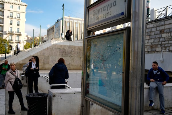 Commuters stand outside the closed main metro Syntagma station, during a nationwide general strike organized by private and public sector unions demanding for better wages, in Athens, Greece, Wednesday, Nov. 20, 2024. (AP Photo/Thanassis Stavrakis)