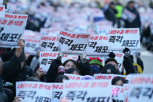 Participants shout slogans during a rally calling on the Constitutional Court to dismiss the President Yoon Suk Yeol, in Seoul, South Korea, Sunday, Dec. 15, 2024. The signs read "Immediately arrest." (AP Photo/Lee Jin-man)