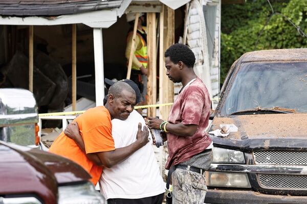 A woman died after a vehicle, allegedly driven by a 14-year-old boy, crashed into her home, according to the Coweta County Sheriff's Office. Andrico Rush, the husband of the victim, hugs his neighbor Sara Brooks while his son Leonard Rush stands nearby.