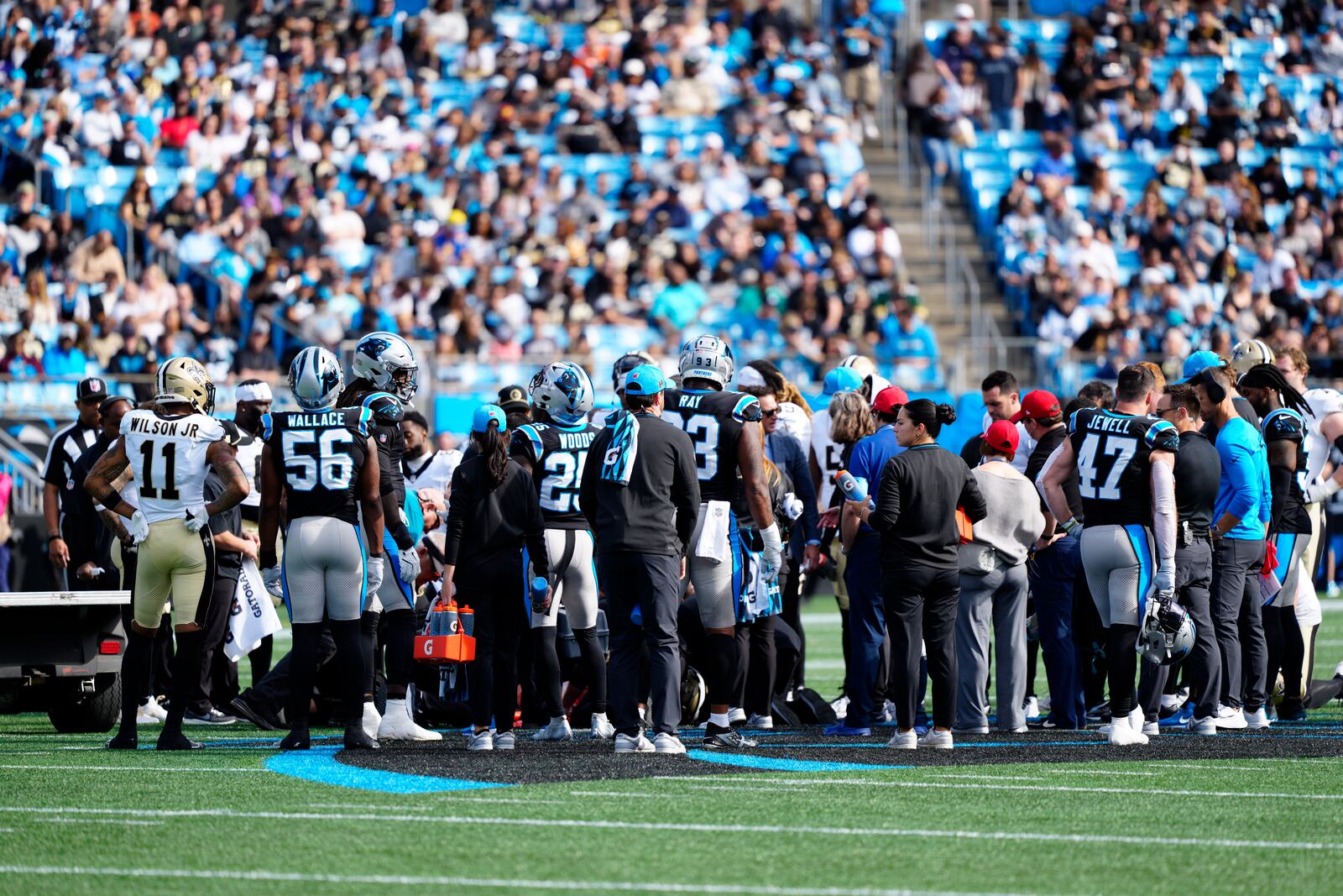 Carolina Panthers and the New Orleans Saints gather around New Orleans Saints wide receiver Chris Olave after he was hurting during the first half of an NFL football game Sunday, Nov. 3, 2024, in Charlotte, N.C. (AP Photo/Jacob Kupferman)