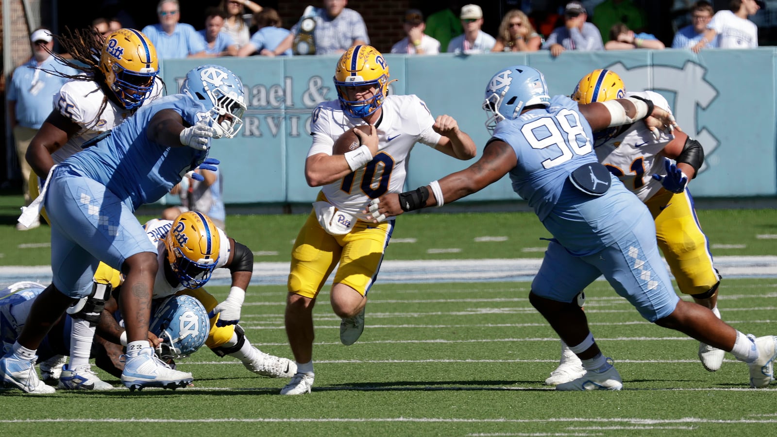 Pittsburgh quarterback Eli Holstein (10) runs thru a hole between North Carolina defensive lineman Travis Shaw, left, and defensive lineman Kevin Hester Jr. (98) during an the second half of an NCAA college football game Saturday, Oct. 5, 2024, in Chapel Hill, N.C. (AP Photo/Chris Seward)