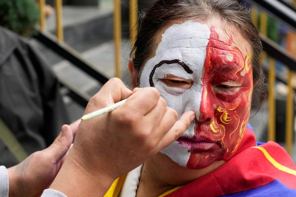 An exiled Tibetan gets her face painted before participating in a march to mark the 66th anniversary of an uprising in Tibetan capital Lhasa, as they gather at the Tsuglakhang temple in Dharamshala, India, Monday, March 10, 2025. (AP Photo/Ashwini Bhatia)