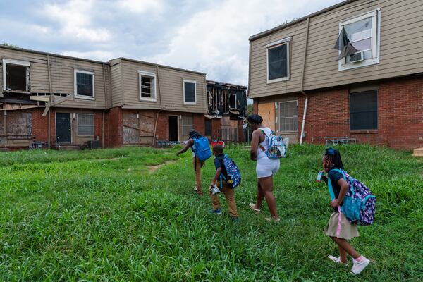 Ayana Meriweather walks with her son and siblings back to the Forest Cove apartments in Atlanta after the bus dropped the children off from Slater Elementary on Thursday, August 18, 2022. For months, the city and community groups have been trying to relocate the condemned complex’s residents but were unable to do so before the school year started. (Arvin Temkar / arvin.temkar@ajc.com)