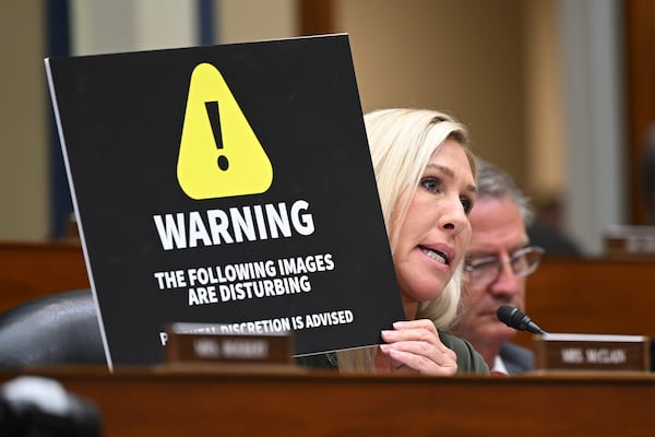 U.S. Rep. Marjorie Taylor Greene (R-Rome) holds up a warning sign during a House Committee on Oversight and Accountability hearing over the tax case against the president's son, Hunter Biden, on Capitol Hill in Washington, July 19, 2023. (Kenny Holston/The New York Times)