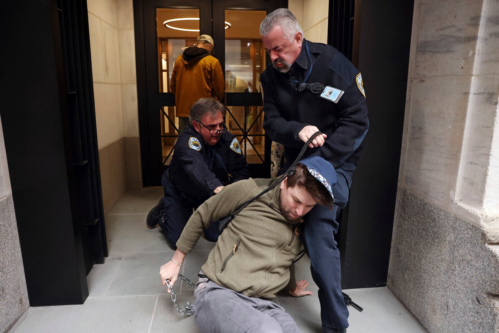 New York Stock Exchange security officers remove demonstrators from one of the building's entrances, Monday, Oct. 14, 2024, in New York. (AP Photo/Yuki Iwamura)