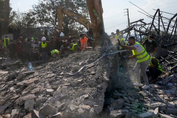 Rescue workers and people search for victims under the rubble of a destroyed house hit in an Israeli airstrike, in Aalmat village, northern Lebanon, Sunday, Nov. 10, 2024. (AP Photo/Hassan Ammar)