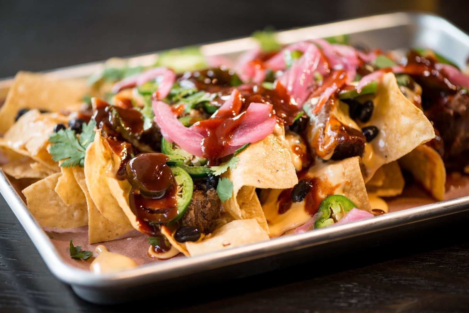 Loyal Tavern offers barbecue nachos, chips and cheese covered with brisket, jalapenos, pickled onions, black beans, cilantro and barbecue sauce. Mia Yakel for The Atlanta Journal-Constitution