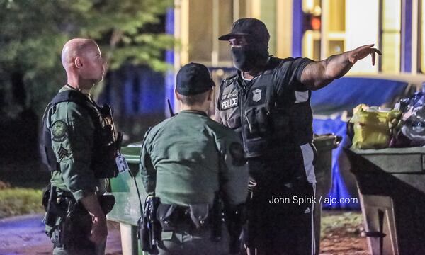 Atlanta officers work the scene of a shooting on Osborne Street in southwest Atlanta Tuesday morning. Someone opened fire on two officers in an unmarked patrol car, setting off an hours-long SWAT standoff and manhunt. JOHN SPINK / JSPINK@AJC.COM