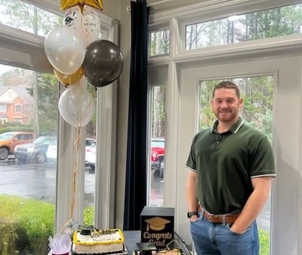 Harrison Olvey stands next to balloons and a cake following his graduation from Kennesaw State.