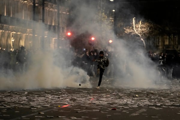 A protester kicks a tear gas canister thrown by riot police during clashes, after the Greek opposition parties have challenged the country's center-right government with a censure motion in parliament over a devastating rail disaster nearly two years ago, in Athens, Wednesday, March 5, 2025. (AP Photo/Petros Giannakouris)