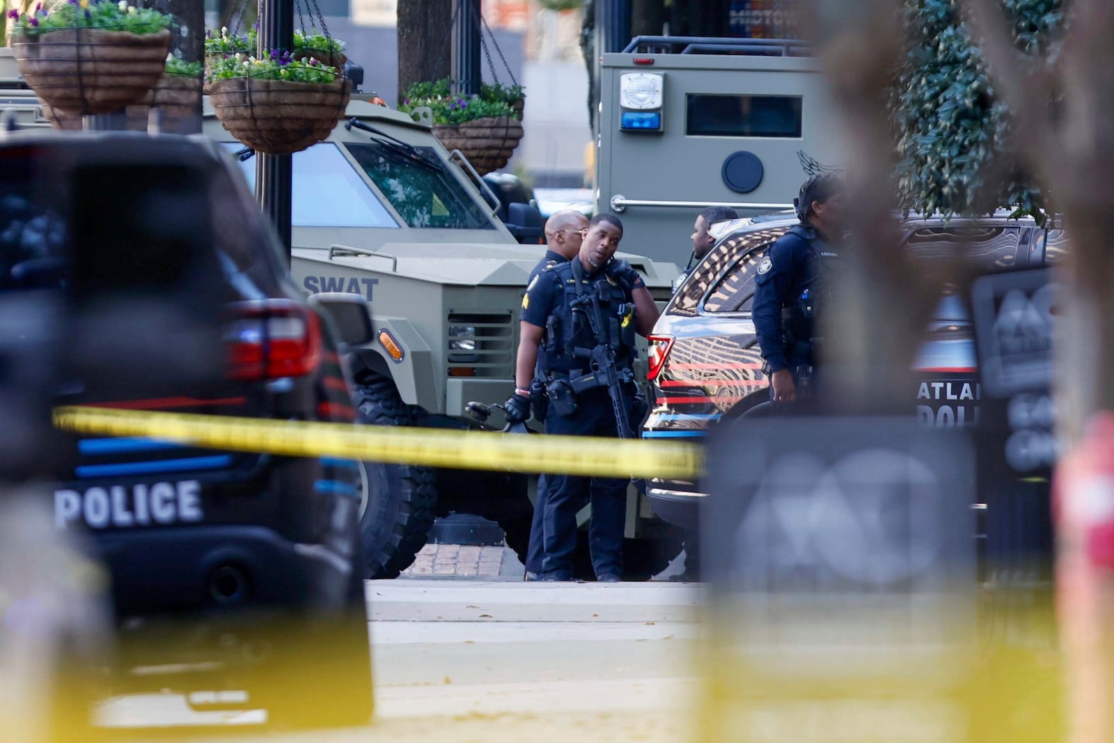 Members of the Atlanta Police Department and SWAT team stand on 14th Street outside the Four Seasons Hotel in the Midtown neighborhood of Atlanta, where a suspect fired shots inside the hotel Tuesday, Oct. 29, 2024. (Miguel Martinez/Atlanta Journal-Constitution via AP)