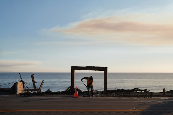 A worker clears debris from the Palisades Fire on Friday, Jan. 10, 2025, in Malibu, Calif. (AP Photo/Eric Thayer)