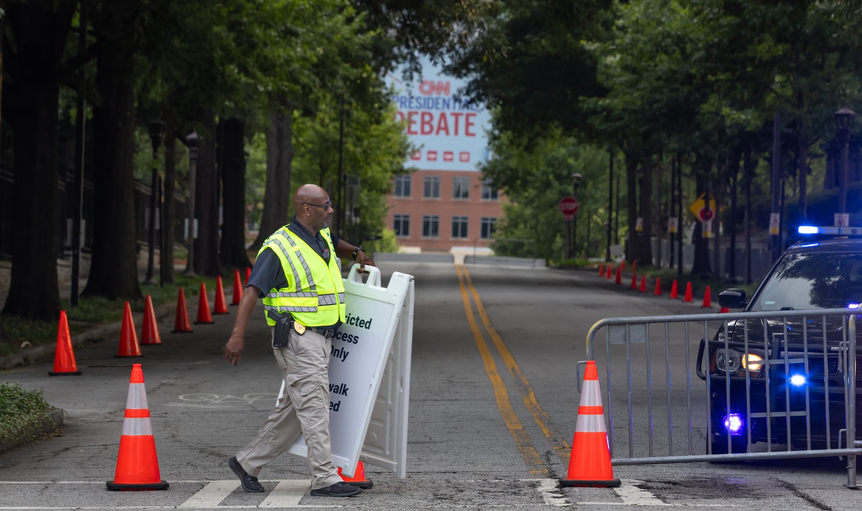 Captain A. Hill with the Georgia Tech Police moves signage into place along Fowler Street and 6th Street as roads closed early Thursday morning, June 27, 2024 near CNN Studios on the Techwood campus in Midtown ahead of Thursday night’s debate between President Joe Biden and former President Donald Trump. The Copa América game between the U.S. National Team and Panama was held at 6 p.m. at Mercedes-Benz Stadium bringing thousands of soccer fans downtown. (John Spink/AJC)