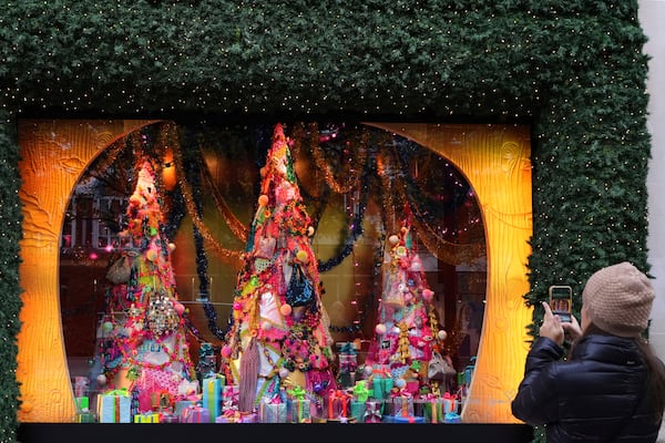 A woman photographs a festive shop window in Oxford Street in London, Friday, Nov. 15, 2024. (AP Photo/Kirsty Wigglesworth)