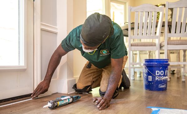 Stephan Carter blocks up air leaks with caulking at a Roswell home, working to make the home more efficient on Wednesday, April 19, 2023. New federal tax credits for home energy improvements incentivize home owners to invest in an energy audit and update air leaks, add insulation and improve home efficiency to get federal tax credits, rebates and other financial benefits including with Georgia Power.  (Jenni Girtman for The Atlanta Journal-Constitution)