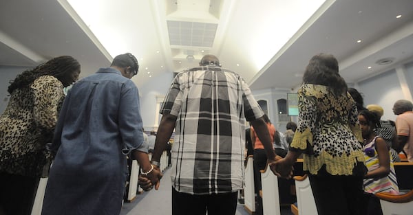 JUNE 26, 2015 NORCROSS Attendees hold hands during a proclamation as Bishop William Sheals, senior pastor of Hopewell Missionary Baptist Church speaks during a town hall meeting against gay marriage in Norcross, Friday, June 26, 2015. In a 5-4 ruling, the U.S. Supreme Court ruled Friday that the Constitution requires states to license same-sex marriage and to recognize same-sex marriages lawfully performed elsewhere. KENT D. JOHNSON /KDJOHNSON@AJC.COM