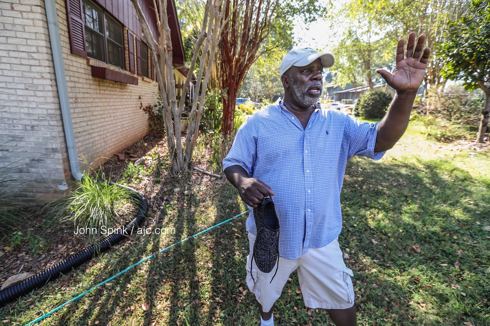 Brian Jenkins holds the shoe left behind by the shooting victim who fell in his yard.