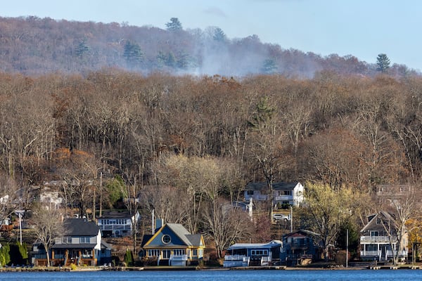 Smoke rises from a wildfire behind a row of lakefront properties in the town of Awosting, as seen from across Greenwood Lake, Lakeside, N.J., Monday, Nov. 11, 2024. (AP Photo/Stefan Jeremiah)