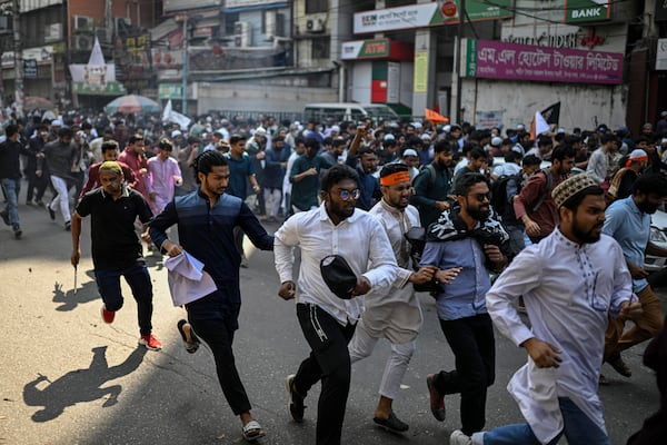 Members and supporters of the banned Islamist group Hizbut Tahrir run after police using tear gas to disperse them near Baitul Mokarram Mosque in Dhaka, Bangladesh, Friday, March 7, 2025. (AP Photo/Mahmud Hossain Opu)