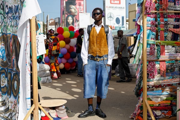 A young man dressed in a thrift outfit poses for a photograph during a thrift and an upcycle show in Accra, Ghana, Sunday, Oct. 27, 2024. (AP Photo/Misper Apawu)