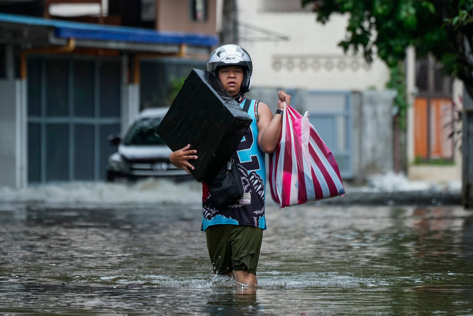 A resident carries belongings as he crosses flooded streets caused by Tropical Storm Trami on Friday, Oct. 25, 2024, in Cainta, Rizal province, Philippines. (AP Photo/Aaron Favila)