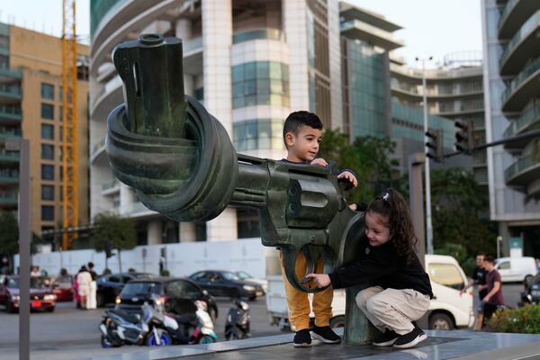 Hussein and Zahraa, 3, displaced Lebanese twins who fled with their parents from their village of Mais al-Jabal in south Lebanon amid the ongoing Hezbollah-Israel, play on a gun with a twisted barrel statute, symbolising anti-violence, in Beirut, Lebanon, Thursday, Oct. 31, 2024. (AP Photo/Hussein Malla)