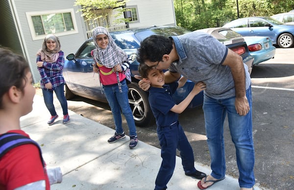 Yaser Musa kisses his son, Issa, 5, outside their Clarkston apartment as he waits for his other children (from left) Samar, 10, Nor Alhoda, 12, and Reem, 11, on April 13, 2017. HYOSUB SHIN / HSHIN@AJC.COM