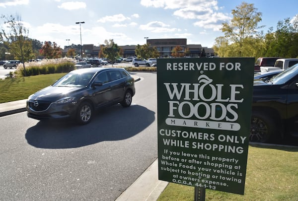 A warning sign at Avalon Whole Foods market parking lot in Alpharetta tells motorists they risk towing or booting if they leave their car after shopping. A bill moving through the Georgia Legislature would make it all-but-illegal to use booting as a method of parking enforcement. HYOSUB SHIN / HSHIN@AJC.COM