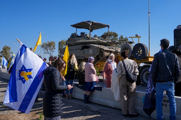 Israelis waiting on the side of a road where the funeral convoy carrying the coffins of slain hostages Shiri Bibas and her two children, Ariel and Kfir, will pass by near Kibbutz Nir Oz, Israel, Wednesday, Feb. 26, 2025. The mother and her two children were abducted by Hamas on Oct. 7, 2023, and their remains were returned from Gaza to Israel last week as part of a ceasefire agreement with Hamas. (AP Photo/Ohad Zwigenberg)