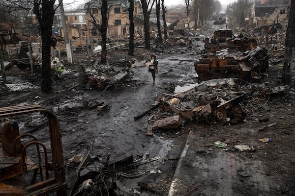 FILE - A woman walks amid destroyed Russian tanks in Bucha, in the outskirts of Kyiv, Ukraine, Sunday, April 3, 2022. (AP Photo/Rodrigo Abd, File)