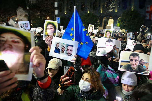 Demonstrators hold portraits of activists injured during protests as they take part in an anti-government rally outside the Parliament building in Tbilisi, Georgia, on Saturday, Dec. 14, 2024. (AP Photo/Zurab Tsertsvadze)