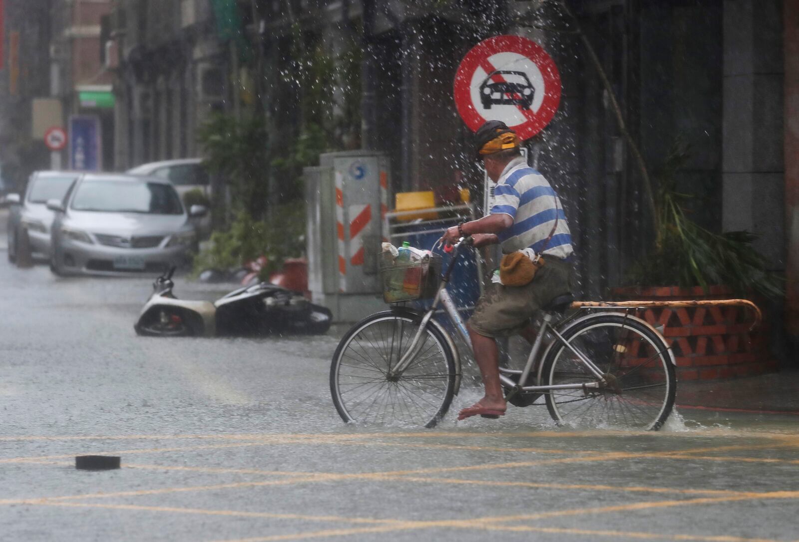 A man pedals through a flooded road as Typhoon Krathon makes landfall in Kaohsiung, southern Taiwan, Thursday, Oct. 3, 2024. (AP Photo/Chiang Ying-ying)