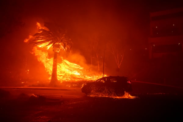 A car drives past flames from the Franklin Fire at Pepperdine University in Malibu, Calif., Tuesday, Dec. 10, 2024. (AP Photo/Eric Thayer)