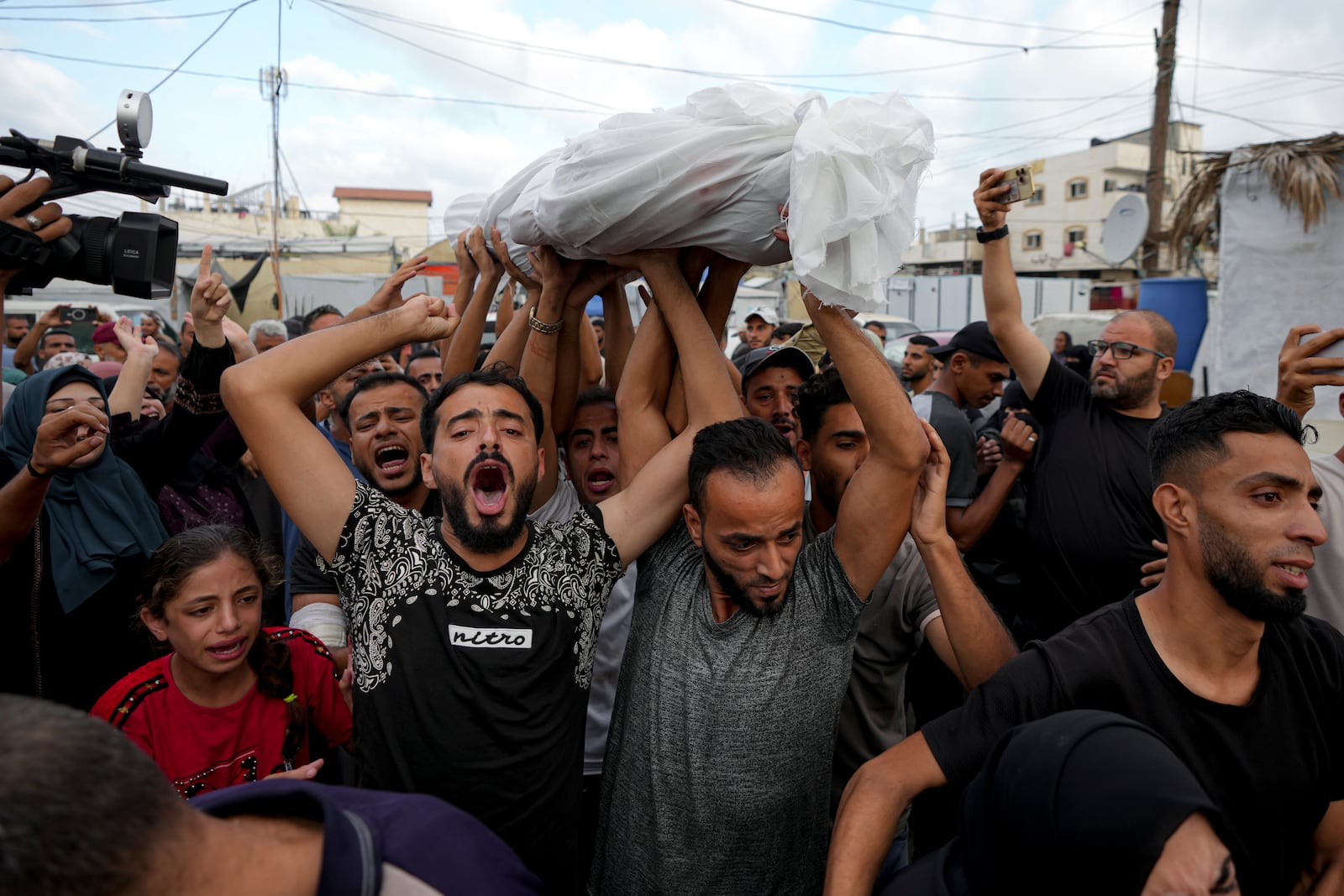 Palestinians mourn as they carry the body of a relative killed in the Israeli bombardment of the Gaza Strip at a hospital in Deir al-Balah, Tuesday, Oct. 8, 2024. (AP Photo/Abdel Kareem Hana)