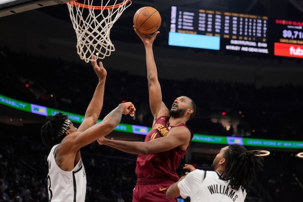 Cleveland Cavaliers forward Evan Mobley, center, shoots between Brooklyn Nets center Nic Claxton, left, and forward Ziaire Williams, right, in the first half of an NBA basketball game Tuesday, March 11, 2025, in Cleveland. (AP Photo/Sue Ogrocki)