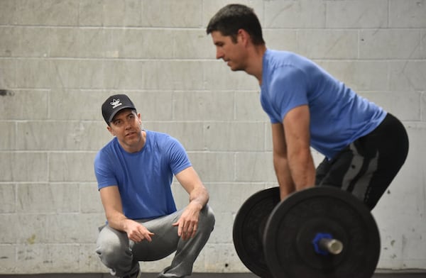 Matt Gunby (left), co-owner/trainer, instructs Mike Schuckenbrock, 43, who has been working out past 7 years and lost 40 lb, at Crossfit East Decatur on Friday, March 15, 2019. HYOSUB SHIN / HSHIN@AJC.COM