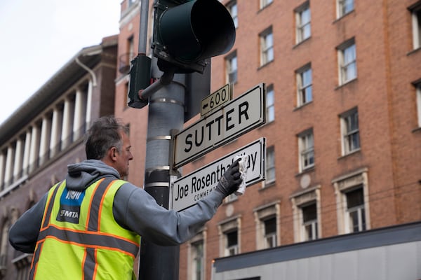 An SFMTA worker installs the Joe Rosenthal Way street sign during the street renaming to honor the former AP photojournalist who won the Pulitzer Prize for his iconic photo of U.S. Marines raising the flag on the Japanese island of Iwo Jima during WWII, Thursday, Dec. 12, 2024, in San Francisco. (AP Photo/Minh Connors)