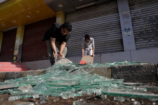 Yemenis clean debris in front of their shops after a U.S. airstrikes in Sanaa, Yemen, Sunday, March 16, 2025. (AP Photo/Osamah Abdulrahman)