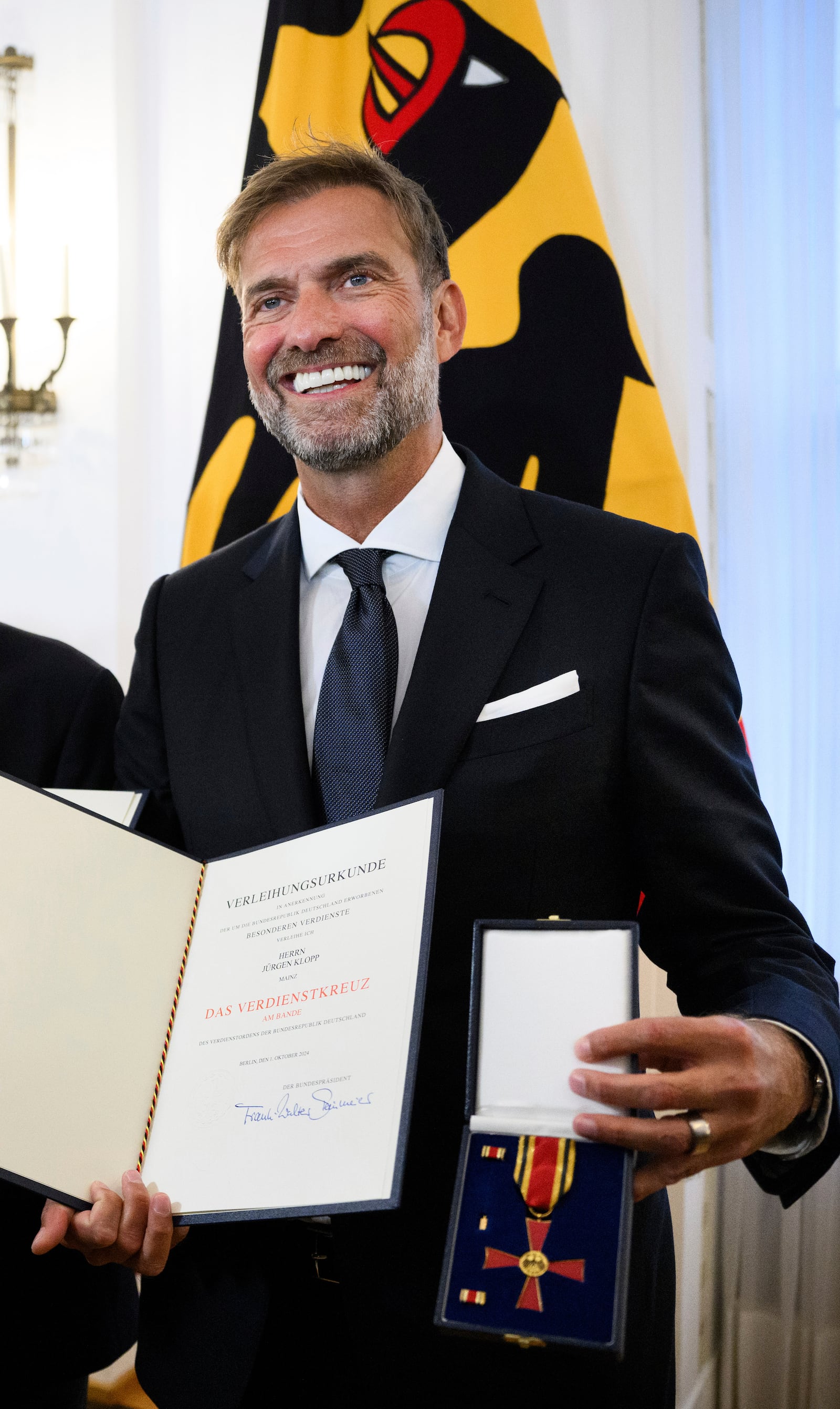 Jurgen Klopp stand in Bellevue Palace after receiving the Order of Merit of the Federal Republic of Germany and show his certificates as Federal President Steinmeier honors 28 citizens on the Day of German Unity, in Berlin, Tuesday, Oct. 1, 2024. (Bernd von Jutrczenka/dpa via AP)