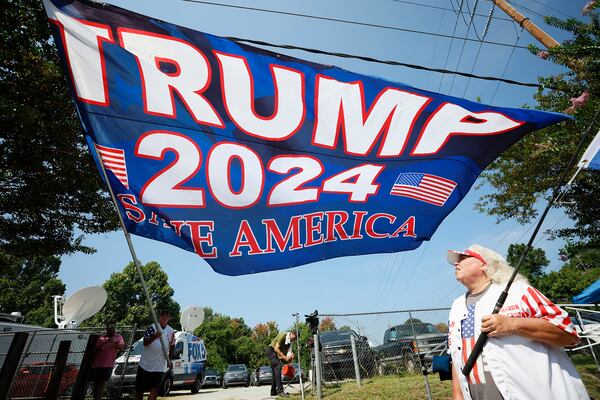 Sharon Anderson from Tennessee watches her friend Mike Boatman from Indiana unfold a 16-by-10 foot Trump flag displayed outside the Fulton County Jail on  August 23, 2023.

Miguel Martinez /miguel.martinezjimenez@ajc.com