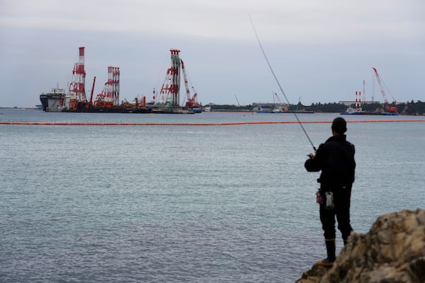 A man tries to catch squid after his night shift, near construction along Camp Schwab, a U.S. Marine Corps base, in Nago, on the main island of the Okinawa archipelago, southern Japan, Tuesday, Feb. 18, 2025. (AP Photo/Hiro Komae)