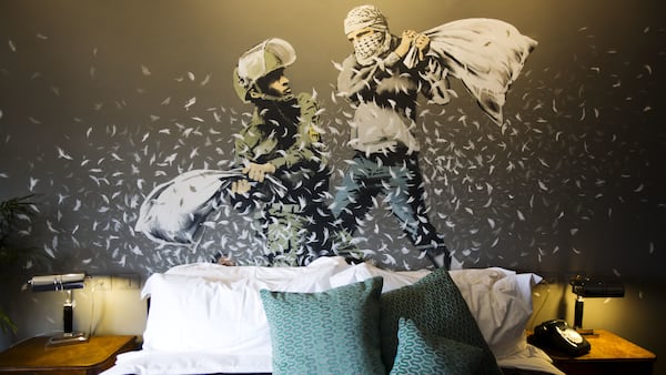 A Banksy wall painting showing Israeli border policeman and Palestinian in a pillow fight is seen in one of the rooms of the "The Walled Off Hotel" in the West Bank city of Bethlehem, Friday, March 3, 2017. The owner of a guest house packed with the elusive artist Banksy's work has opened the doors of his West Bank establishments to media, showcasing its unique "worst view in the world." The nine-room hotel named "The Walled Off Hotel" will officially open on March 11. (AP Photo/Dusan Vranic)