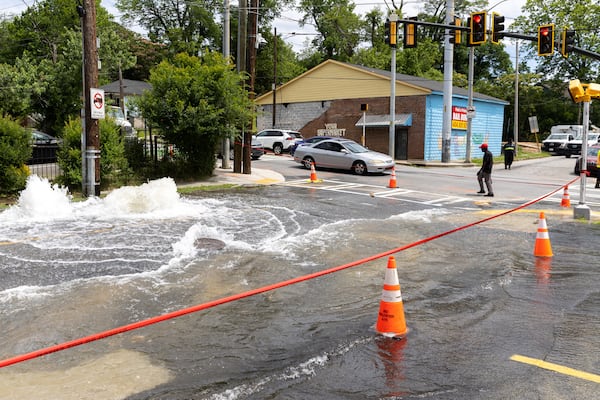 A pedestrian walks by a water main break at Joseph E. Boone Boulevard and James P. Brawley Drive in Atlanta on May 31, 2024. (Arvin Temkar/The Atlanta Journal-Constitution/TNS)