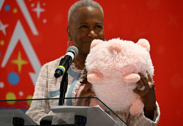 Monica Pearson holds a pink pig doll as she moderates during a press conference reintroducing the Pink Pig, a ride that goes back to 1953 at Rich's department store and became an Atlanta tradition, at Gas South Conference Center on Saturday, July 27, 2024, in Duluth. (Hyosub Shin / AJC)