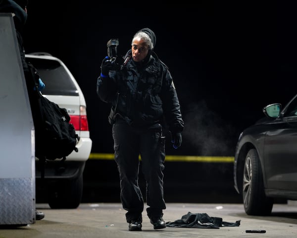 A crime scene technician with a camera processes a shooting scene at a BP station at 3550 Campbellton Road on Thursday morning. A man was killed, according to Atlanta police.