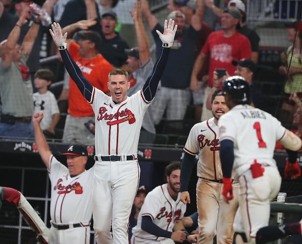 Atlanta Braves (from left) manager Brian Snitker, first baseman Freddie Freeman and catcher Travis d'Arnaud react as second baseman Ozzie Albies rounds the bases after hitting a 3-run walk-off homer for an 8-6 victory over the Cincinnati Reds.   “Curtis Compton / Curtis.Compton@ajc.com”