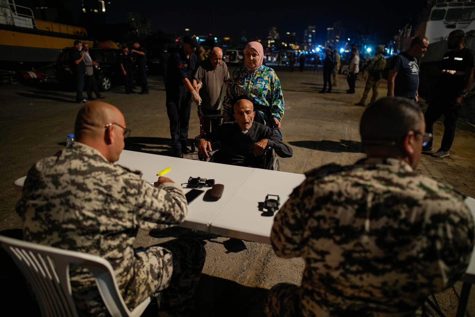 Lebanese security officials verify the travel documents of Turkish citizens before boarding Turkish military ships to evacuate them from Lebanon to Turkey, in Beirut port on Wednesday, Oct. 9, 2024. (AP Photo/Emrah Gurel)